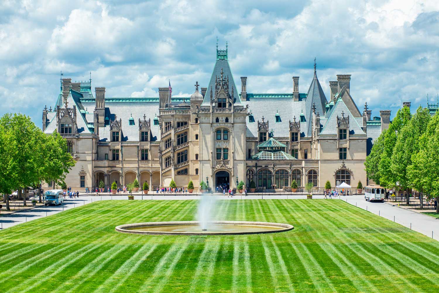 a beautiful castle with the lawn and a fountain