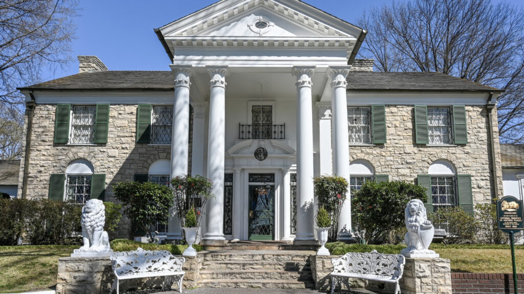 the front of the building with four white columns and lion statues