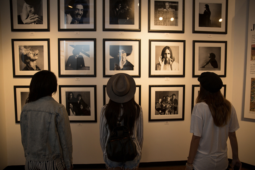 three women are looking at black and white pictures on the wall