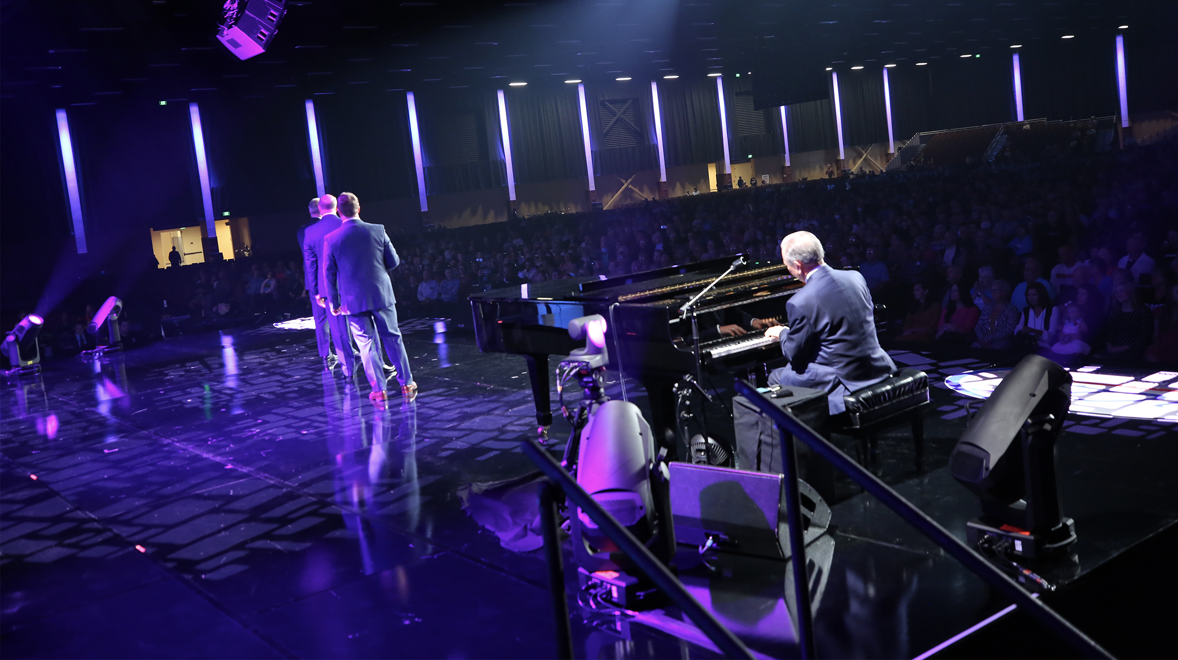 men on the stage are singing and playing piano