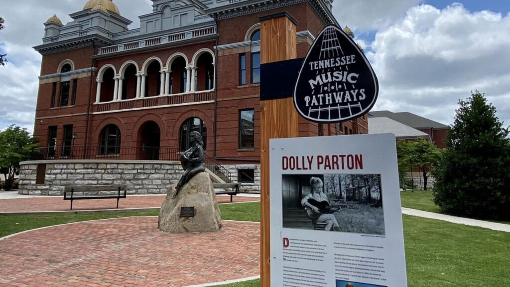 Tennessee Music Pathway sign with the article about Dolly Parton and statue behind it