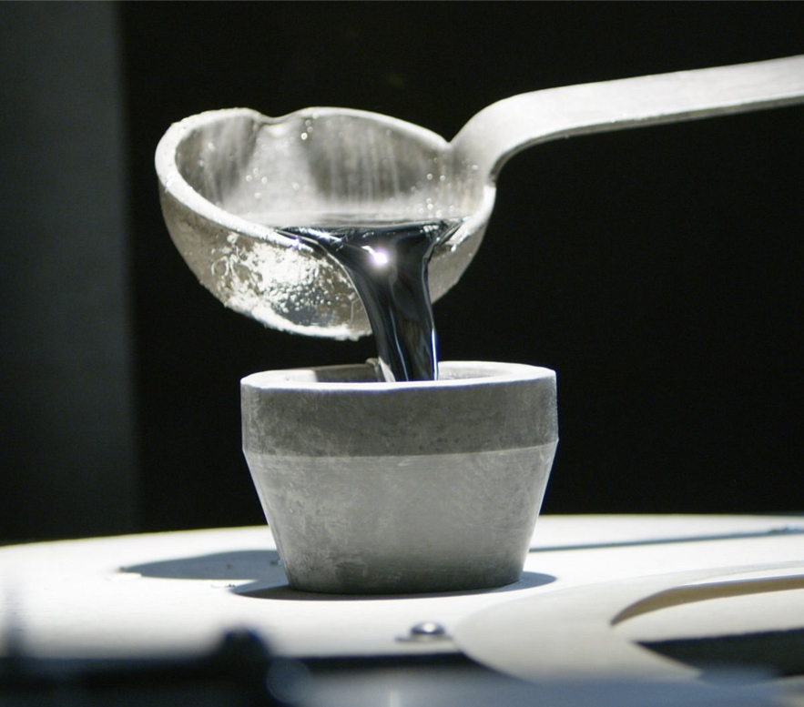 a liquid metal pouring from the ladle into a cup