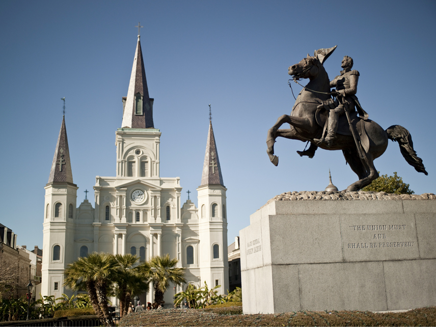 a statue of the man on the horse in front of the white building with pointy towers